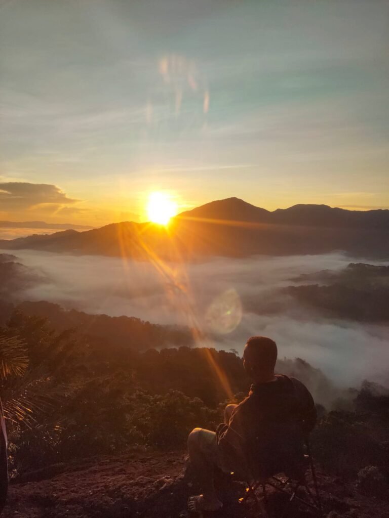 Sunrise trekking at Watu Benta, Flores, with travelers walking along grassy ridges under warm morning light and scenic highland views