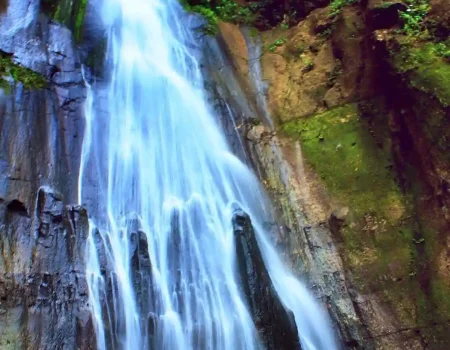 Mataru Waterfall, the highest waterfall in Alor, cascading from tall cliffs surrounded by lush green forest in Pulau Alor, Indonesia.