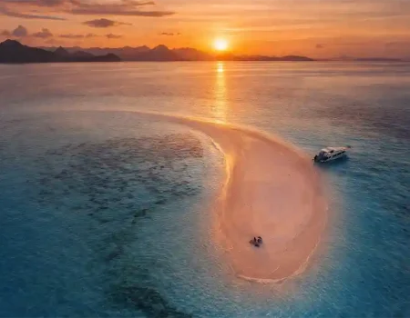 Aerial view of Taka Makassar sandbar in Komodo National Park, featuring crescent-shaped white sand surrounded by turquoise waters in the Flores Sea near Labuan Bajo