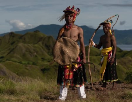 Traditional Caci whip dance performance in Flores, Indonesia, showcasing dancers in vibrant costumes demonstrating ritual combat and cultural heritage.